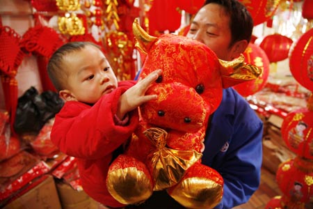 A child touches a doll cow bought by his father at a market in Guiyang, capital of southwest China's Guizhou Province, on January 13, 2009. People are busy in selecting decorations and goods to greet the Chinese traditional Spring Festival, which falls on January 26 this year.