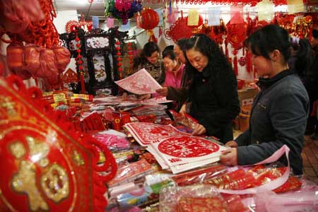 People select paper-cut decorations at a market in Guiyang, capital of southwest China's Guizhou Province, on January 13, 2009. People were busy in selecting all kinds of decorations and goods to greet the Chinese traditional Spring Festival, which falls on January 26 this year. 