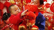 A child touches a doll cow bought by his father at a market in Guiyang, capital of southwest China's Guizhou Province, on January 13, 2009. People were busy in selecting decorations and goods to greet the Chinese traditional Spring Festival, which falls on January 26 this year.