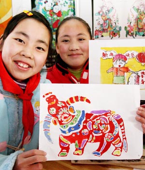 Two girls shows their handmade Taohuawu woodcut New Year paintings in Taowu Central Elementary School in Suzhou, east China's Jiangsu Province, Jan. 14, 2009. An activity with the theme of greeting the Chinese Year of Ox was held here during which pupils made Taohuawu New Year paintings and presented to their parents, friends and teachers. (Xinhua/Wang Jianzhong)