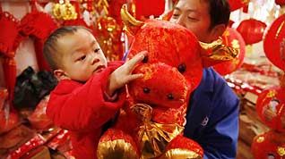 A child touches a doll cow bought by his father at a market in Guiyang, capital of southwest China's Guizhou Province, on January 13, 2009. People were busy in selecting decorations and goods to greet the Chinese traditional Spring Festival, which falls on January 26 this year.