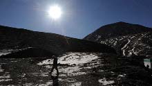 A foreign tourist walks along the Karola glacier, which situates at the boundary between the Nagarze county and the Gyangze county of southwest China's Tibet Autonomous Region, on January 14, 2009. The glacier tongue locates at an altitude of 5,560 meters, extending from the top to the roadside.