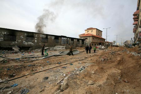 Palestinian people walk past a destroyed area after Israeli military operations in the Tal al Hawa area of Gaza City, on January 16, 2009. The death toll in Gaza has risen to more than 1140 since the beginning of the Israeli massive attack on Gaza on December 27, 2008, with about 5150 wounded, Gaza emergency chief Mo'aweya Hassanein said on Friday. [Xinhua]