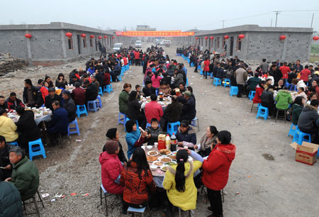 Villagers celebrate for moving to permanent dwellings in front of their new residences at Anren Village of Mianzhu City, southwest China's Sichuan Province, on January 18, 2009. A total of 332 Anren villagers whose houses collapsed or dilapidated during the May 12 massive earthquake last year feasted on Sunday to celebrate the resettlement. [Xinhua]