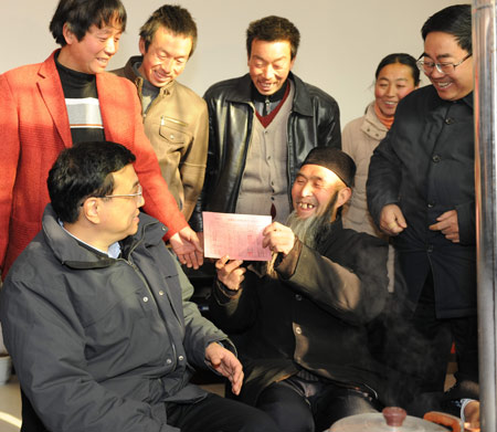 Villager Zhao Danlin (2nd L, front) displays his relief coupon to Chinese Vice Premier Li Keqiang (L, front) in the Longtou Village of Longnan City, in northwest China's Gansu Province, on January 16, 2009.