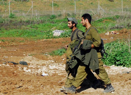 Israeli soldiers walk on Israel-Gaza border after returning from the Gaza Strip on January 18, 2009. The Israeli army has begun withdrawing its troops from the Gaza Strip on Sunday evening, local news service Ynet reported.