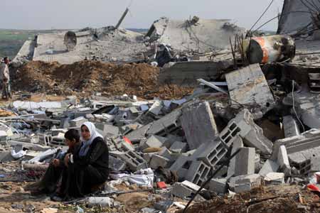 Palestinians sit in front of destroyed houses by Israeli strikes in the east of northern Gaza Strip, on January 19, 2009. Right after a ceasefire was declared by both Israel and Gaza militant groups, thousands of Gaza residents went back to their homes they had fled during the war, only to see how huge the destruction was.