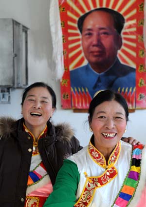 Two smiling women of the Tibetan ethnic group pose for a picture in front of the portrait of late Chinese leader Mao Zedong, in Lhasa, capital of southwest China's Tibet Autonomous Region, on January 19, 2009.