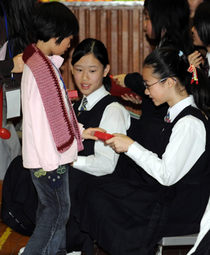 Xia Fengting (L), a little girl from the quake-hit area in southwest China's Sichuan Province, presents the souvenir to a student in Hong Kong, south China, on January 19, 2009.