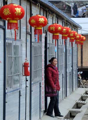 A woman walks out of a temporary dwelling decorated with red lanterns in Chenjiaba Township of Beichuan County, southwest China's Sichuan Province, on January 20, 2009, before the Chinese lunar New Year starts from Jan. 26. Beichuan was one of the areas hit most seriously by the May 12 earthquake last year.