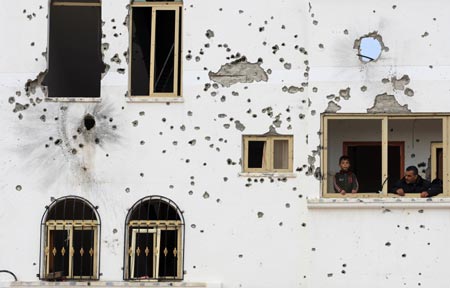 Palestinians look out of the balcony of the house damaged in Israeli military strikes in the al-Zaitoun neighborhood in southeast Gaza City, on January 20, 2009.