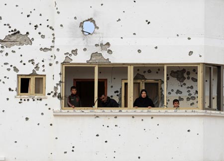 Palestinians look out of the balcony of the house damaged in Israeli military strikes in the al-Zaitoun neighborhood in southeast Gaza City, on January 20, 2009.