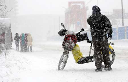 A motorcyclist stands in snow in Shenyang, capital of northeast China's Liaoning Province, on January 22, 2009.