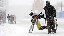 A motorcyclist stands in snow in Shenyang, capital of northeast China's Liaoning Province, on January 22, 2009.