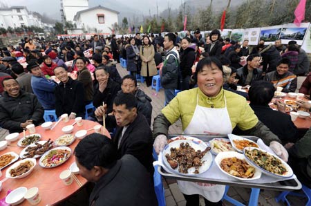 A woman serves with big smile on her face during a banquet to celebrate moving into new house in Dongjiaxinyuanzi town of Dujiangyan City, southwest China's Sichuan Province, on January 22, 2009. As their homestead was destroyed in the earthquake in May 2008, about 400 families in Dongjiaxinyuanzi town moved to new houses on January 22.