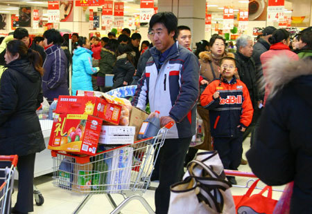 A local resident shop for 'festival necessities' for the upcoming Chinese Lunar New Year at a supermarket in Beijing, on January 23, 2009. [Xinhua]