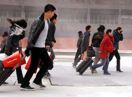 Passengers walks forward against chill and gale to railway station in Shanghai, east China, on January 23, 2009.