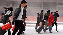 Passengers walks forward against chill and gale to railway station in Shanghai, east China, on January 23, 2009.