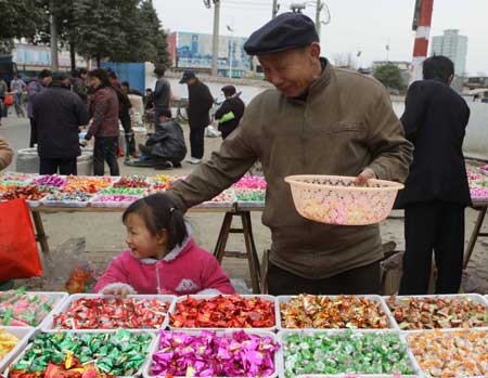 Four-year-old Su Juan (L) selects candies with her grandfather for the imminent Spring Festival at Hanzhong, a quake-hit city of northwest China's Shaanxi Province, Jan. 23, 2009.