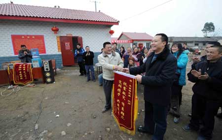 Villagers send a silk banner to the local authority on the completion ceremony of their newly rebuilt houses at Shifang, a quake-hit city of southwest China's Sichuan Province, Jan. 23, 2009.