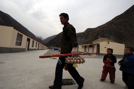 A man carries home the goods bought for the Lunar New Year at Songba village in Wenxian County of Longnan City, northwest China's Gansu Province, on January 23, 2009. A total of 66 quake-affected families at Songba village moved into 216 new houses before the Chinese Lunar New Year.