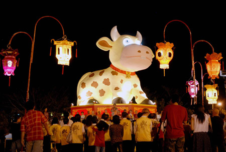 People gather around an illuminated lamp in the shape of ox at a temple in Malaysia on January 23, 2009.