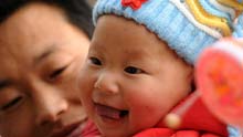 Baby Gao Zhen smiles in his father' s arms in Shuicaogou Village in Wenxian County of Longnan City, northwest China's Gansu Province, on January 24, 2009. Gao Zhen with the nickname Zhensheng which means born on the day of the earthquake happened was dressed in new clothes to celebrate the coming Spring Festival.