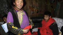 Gou Andong (R), who was transferred from Yingxiu Township by Chinese Premier Wen Jiabao' s special plane after earthquake on May 14, 2008, is seen with his family at a temporary dwelling in Longxi Village, Longxi Town of Wenchuan County in southwest China's Sichuan Province, on January 23, 2009.