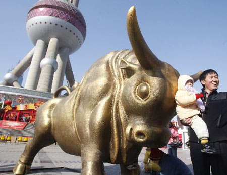 Tourists pose for photographs besides an Ox statue with the landmark tower of Shanghai Oriental Pearl in the background, celebrating the upcoming Chinese Lunar New Year of Ox, in Shanghai Saturday, on January 24, 2009.