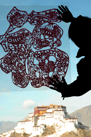 A man sticks a paper-cut of Chinese character of 'Fu', meaning 'good fortune', onto the window at a cafe to celebrate the Spring Festival in Lhasa, capital of southwest China's Tibet Autonomous Region, on January 25, 2009.