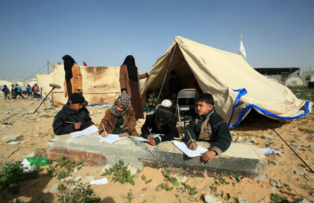 Palestinian pupils attend a class outside their destroyed school in Rafah, southern Gaza Strip, on January 25, 2009.