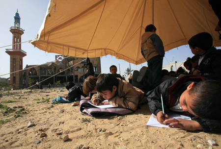 Palestinian pupils attend a class outside their destroyed school in Rafah, southern Gaza Strip, on January 25, 2009.