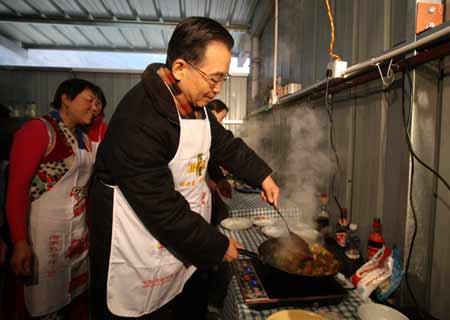 Chinese Premier Wen Jiabao (R) cooks at a kitchen shared by several families at the prefabs in Yingxiu Township of Wenchuan County, southwest China's Sichuan Province, on January 25, 2009. Wen Jiabao came to the quake-hit counties of Beichuan, Deyang and Wenchuan in Sichuan Province on January 24 and 25, celebrating the Spring Festival with local residents.
