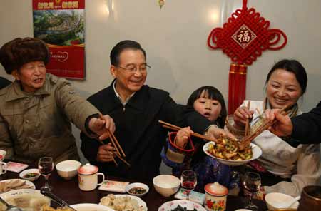 Chinese Premier Wen Jiabao (2nd L) shares the twice-cooked pork slices he cooked with family members of local resident Wu Zhiyuan, in Yingxiu Township of Wenchuan County, southwest China's Sichuan Province, on January 25, 2009. Wen Jiabao came to the quake-hit counties of Beichuan, Deyang and Wenchuan in Sichuan Province on Janury 24 and 25, celebrating the Spring Festival with local residents.