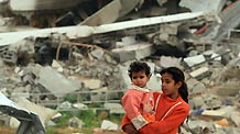 A Palestinian girl holding a child stand before buildings destroyed in Israeli military operations in Zitton, southern Gaza City, on January 24, 2009. A large number of houses were destroyed in the conflict in Gaza Strip. [Xinhua]