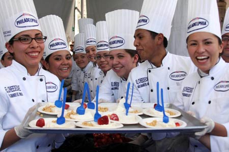 Chefs display pieces of a giant cheesecake that broke Guinness World Record for the biggest cheesecake of the world in Mexico City, capital of Mexico, on January 25, 2009. The cheese cake, with 2.5 meters in diameter, 55 centimeters in height and 2 tons in weight, was made by 55 chefs and 5 student chefs and cost 800 kilograms of cheese.