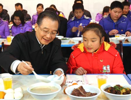 Chinese Premier Wen Jiabao (L) ladles porridge for Zhu Ke, a school girl, at the cafeteria of Beichuan Middle School in Beichuan County, southwest China's Sichuan Province, on January 24, 2009. Wen Jiabao came to the quake-hit counties of Beichuan, Deyang and Wenchuan in Sichuan Province on January 24 and 25, celebrating the Spring Festival with local residents. 