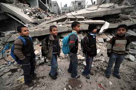 Palestinian students pass by a destroyed building on their way to school in Jibaliya, northern Gaza Strip, on January 27, 2009. All schools in the war-battered Gaza Strip reopened on January 24. [Xinhua]