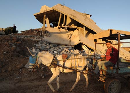 A mule cart passes by the houses of Mahamad Abd Raabo in Jibaliya, northern Gaza Strip, on January 27, 2009. The two-floor building which costed 18-year hard work of Abd Raabo was damaged during Israeli military attacks. Abd Raabo and his wife are unwilling to leave and still living in it. [Xinhua]