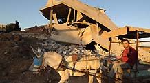 A mule cart passes by the houses of Mahamad Abd Raabo in Jibaliya, northern Gaza Strip, on January 27, 2009. The two-floor building which costed 18-year hard work of Abd Raabo was damaged during Israeli military attacks. Abd Raabo and his wife are unwilling to leave and still living in it. [Xinhua]