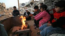 Palestinians get warm by a fire in the rubbles in al Moghraqa area in the central Gaza Strip, on January 29, 2009. The reconstruction of Gaza Strip after a ceasefire is almost at a standstill due to the continuous blockage of Gaza by Israel and different opinions on receiving international aid in the Palestinian side.