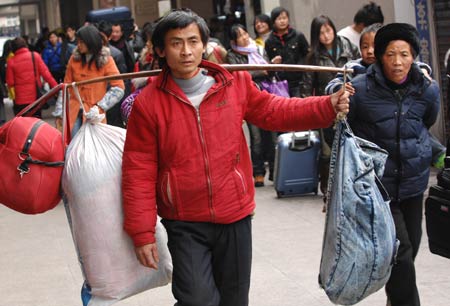 A migrant worker, with luggages on his shoulder, walks out of Hangzhou Railway Station in Hangzhou, east China's Zhejiang Province, on January 30, 2009. As the Spring Festival holiday is about to finish, passenger transportation of the Spring Festival started to reach the peak of return passengers.