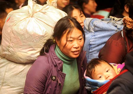 A woman bearing a big luggage walks out of Hanzhou Railway Station, in Hangzhou, capital of east China's Zhejiang Province, on January 30, 2009. The station witnessed the first returning travel peak of migrant workers after the Spring Festival on Friday.