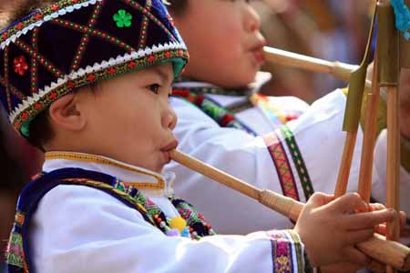 A brightly-attired boy of the ethnic Miao group absorbs in blowing the Luseng flute during a frolic of Luseng (a reed-pipe Bamboo-cluster flute) dance of hall-stepping, a gala drawing many little boys of the ethnic Miao group to bring forth their skillful Luseng flute dancing, at Sirong Township, Rongshui Miao Autonomous County, southwest China's Guangxi Zhuang Autonomous Region, on January 29, 2009.