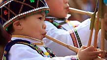 A brightly-attired boy of the ethnic Miao group absorbs in blowing the Luseng flute during a frolic of Luseng (a reed-pipe Bamboo-cluster flute) dance of hall-stepping, a gala drawing many little boys of the ethnic Miao group to bring forth their skillful Luseng flute dancing, at Sirong Township, Rongshui Miao Autonomous County, southwest China's Guangxi Zhuang Autonomous Region, on January 29, 2009.