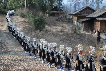 Women dressed in the costume of Miao ethnic group walk in line in the Zhanliu Village of Jianhe County, southwest China's Guizhou Province, on January 31, 2009.