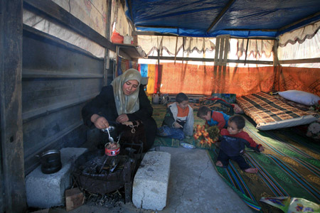 A Palestinian family who lost their home during the 22-day Israeli offensive sit by a small fire in a tent in Jabalia, northern Gaza Strip, on January 31, 2009.