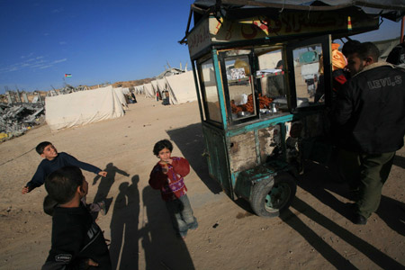 Children stand by a cart selling sweets at a camp of Palestinians who lost their homes during the 22-day Israeli offensive in Jabalia, northern Gaza Strip, on January 31, 2009.