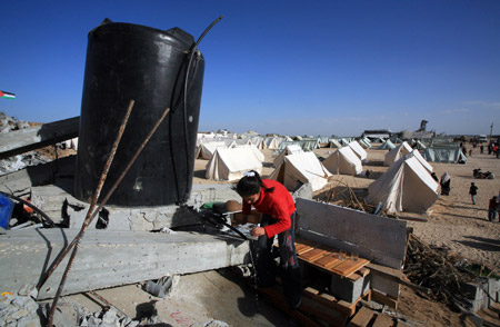 A Palestinian girl who lost her home during the 22-day Israeli offensive washes cups at a refugee camp in Jabalia, northern Gaza Strip, on January 31, 2009. 