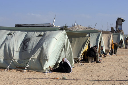 Palestinians who lost their home during the 22-day Israeli offensive sit by tents at a refugee camp in Jabalia, northern Gaza Strip, on January 31, 2009.